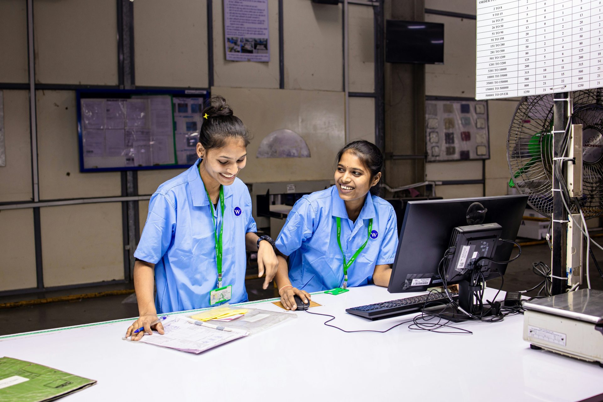 Two women working at a desk and smiling.